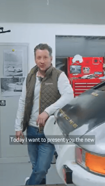 man in a garage next to a historic Porsche car