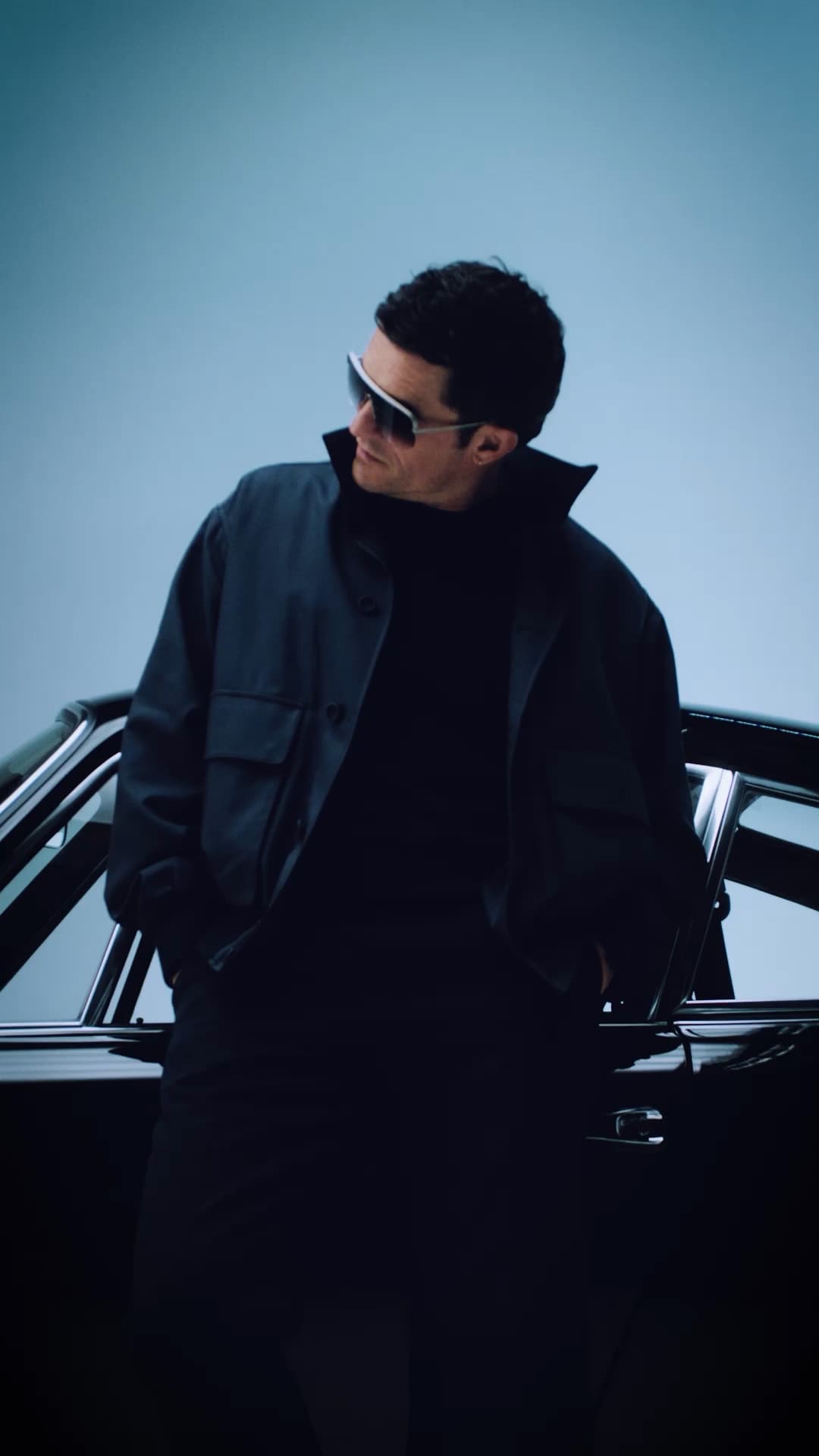 Orlando Bloom wearing Porsche Design Iconic Targa Sunglasses standing in front of a Porsche 911 Targa