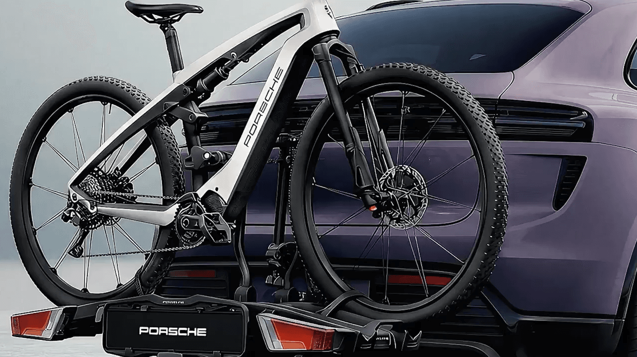 Porsche bike mounted on a purple car's rear, showcasing sleek design and black tires against a neutral background.